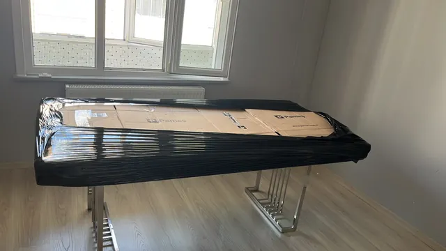 Karton ve siyah koruyucu filmle paketlenen masa parçası